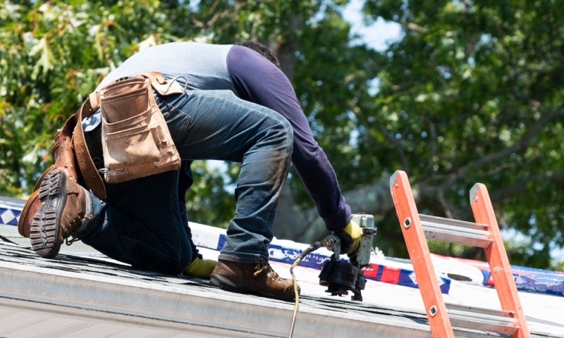 roofer fastening shingles with a nail gun